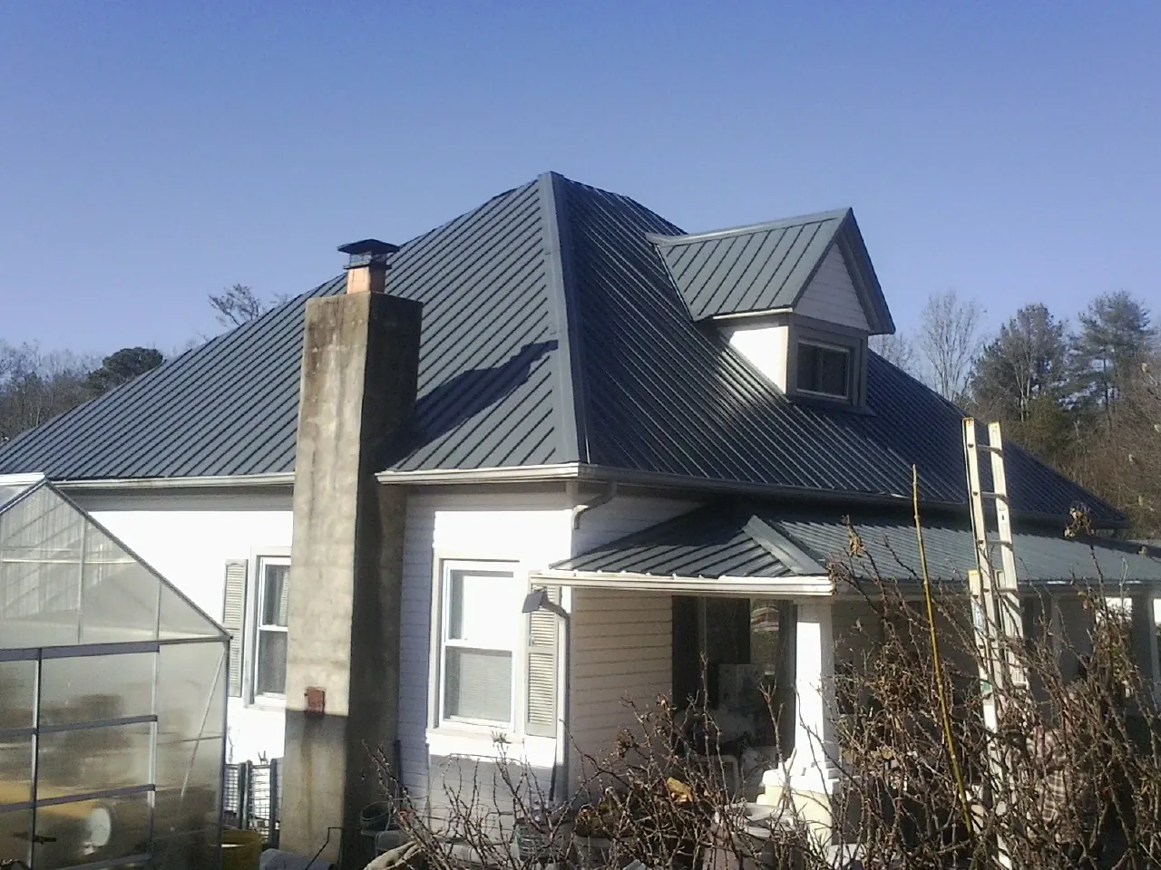 Dark blue standing seam metal roof on a white farmhouse with dormer — Slate & Tile Roof Repair by Roofing Brothers in Lucasville