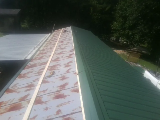 Old rusted panels beside newly installed green metal roofing — Wind Damage Roof Repair by Roofing Brothers in Lucasville