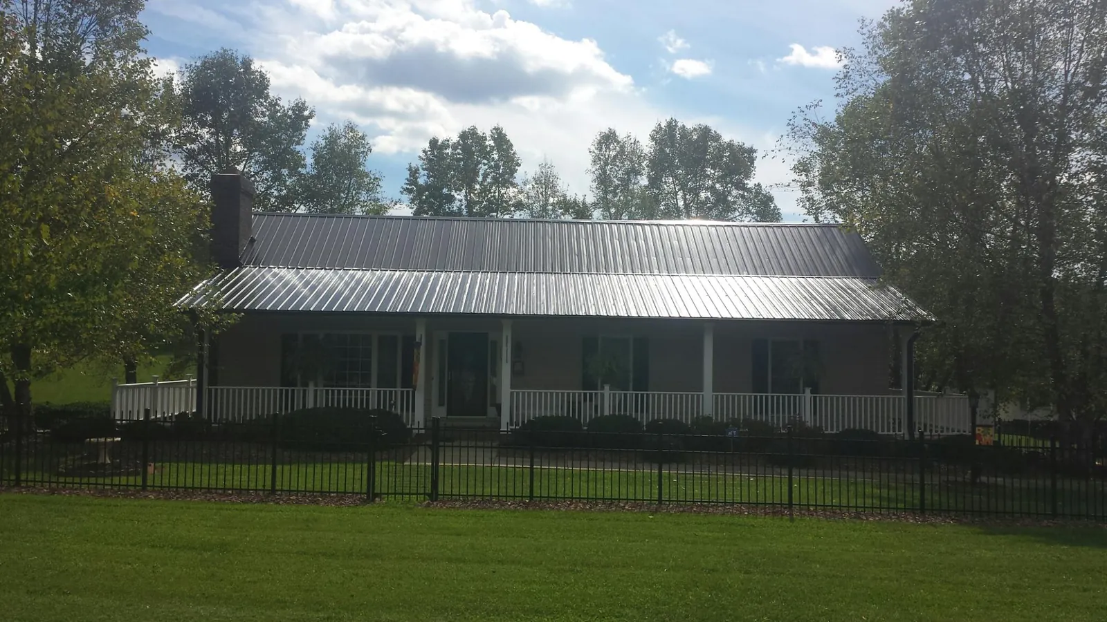 Gray metal roof on a brick ranch with a full width front porch — Gutter Guard Installation work by our crew in Lucasville
