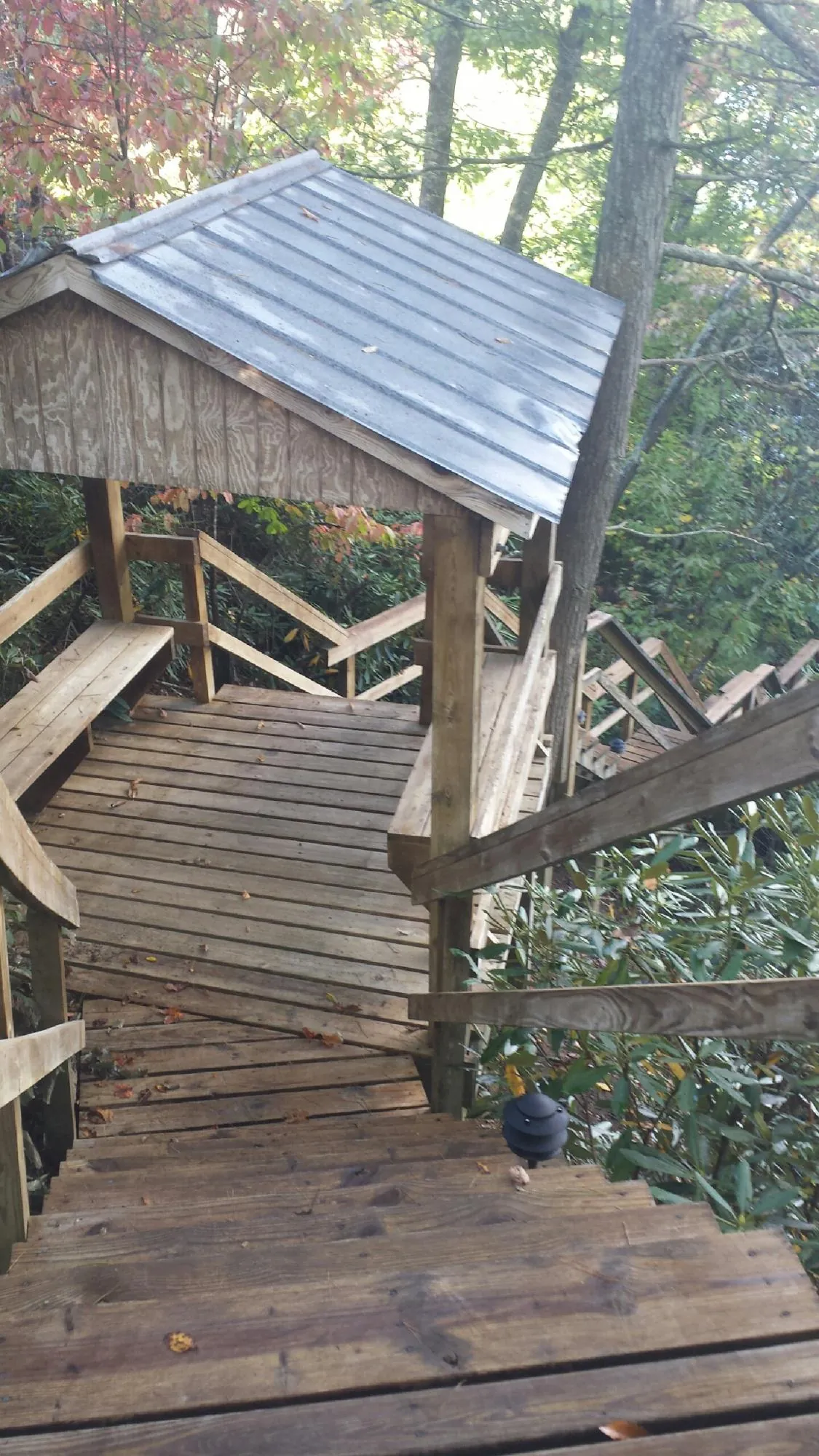 Metal roofed shelter over wooden steps on a wooded walkway — Skylight Repair & Installation work by our crew in Lucasville