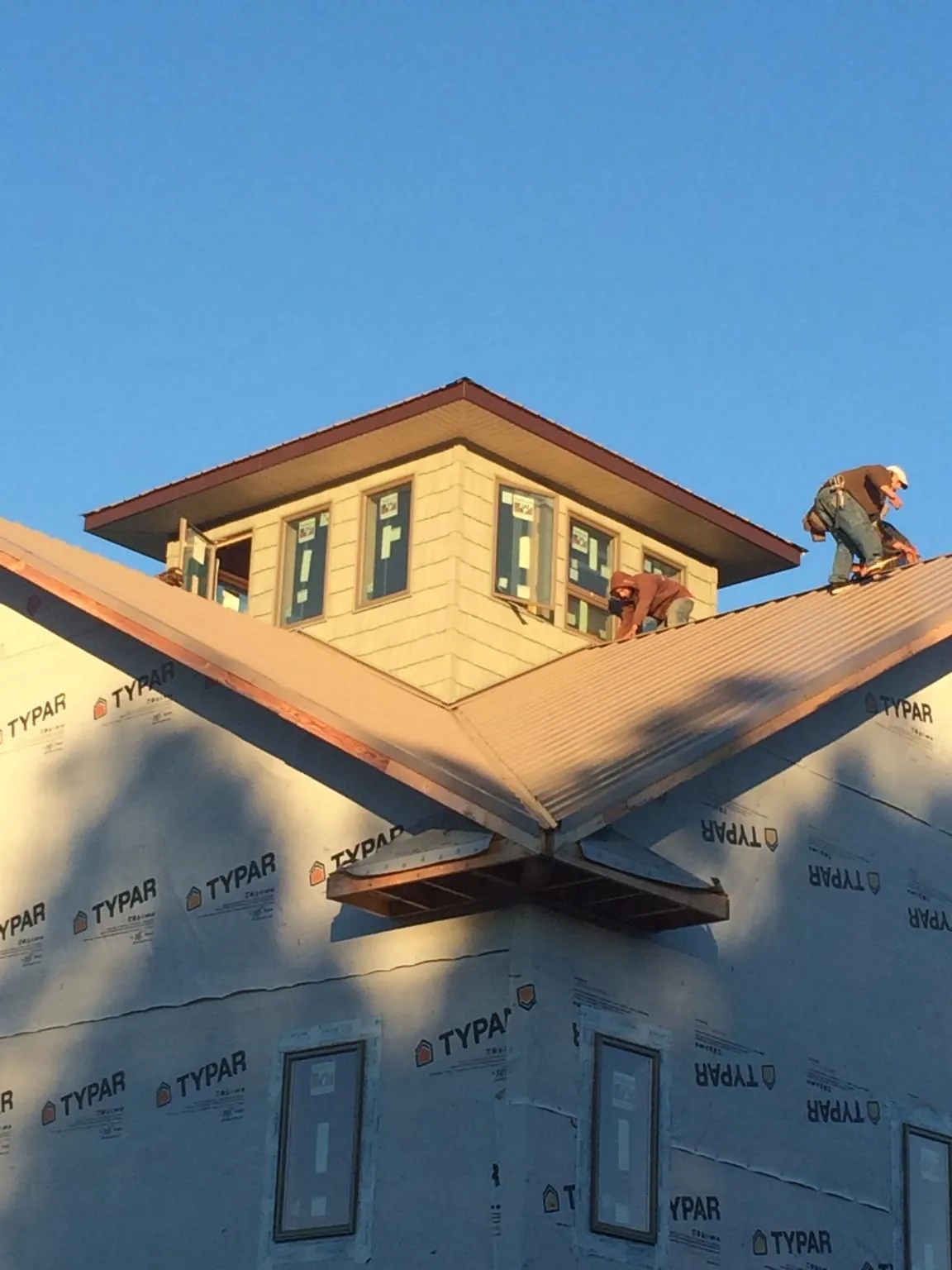 Roofers working around a rooftop cupola on a new metal roof at sunset — Roof Waterproofing in Lucasville by Roofing Brothers